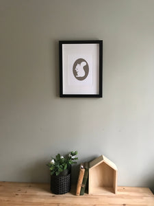 Giclee Art print of gray squirrel holding acorn in white fine art paper shown in frame hanging on wall